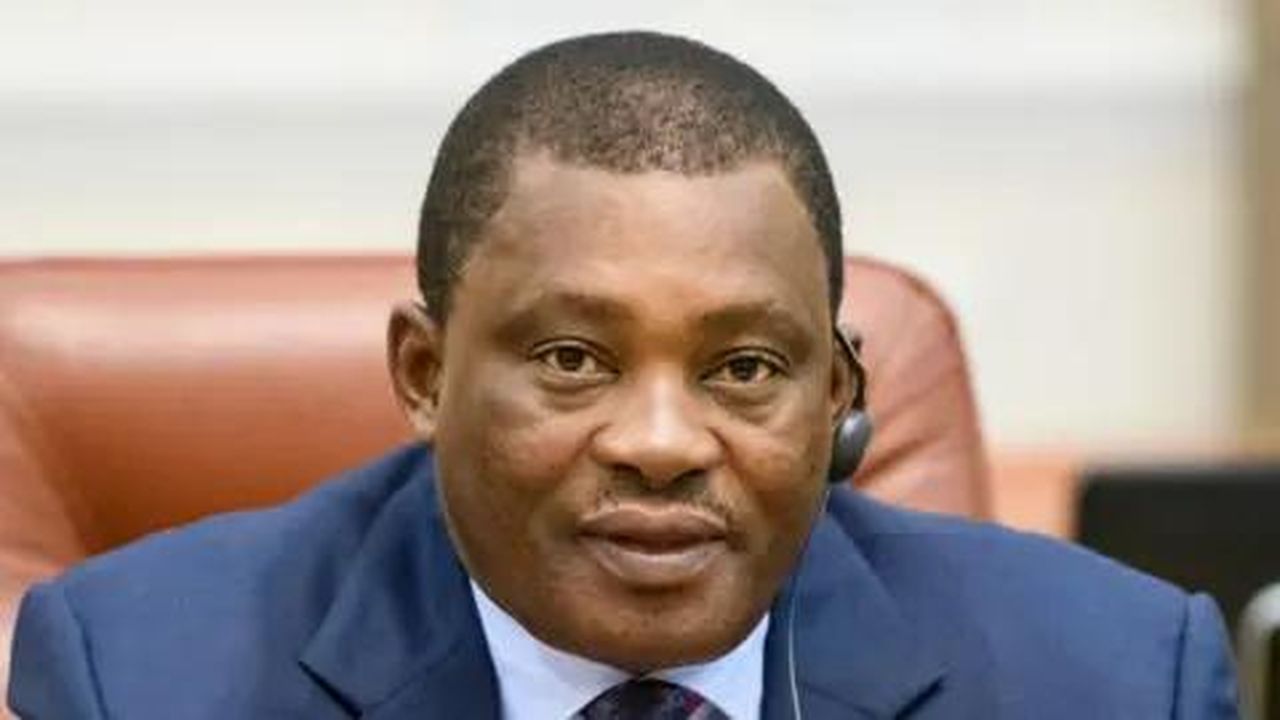 source:BBC World News - Accuse del ministro Muturi - Il Segretario del Gabinetto per il Servizio Pubblico Justin Muturi parla in un microfono mentre è seduto su una sedia di pelle.