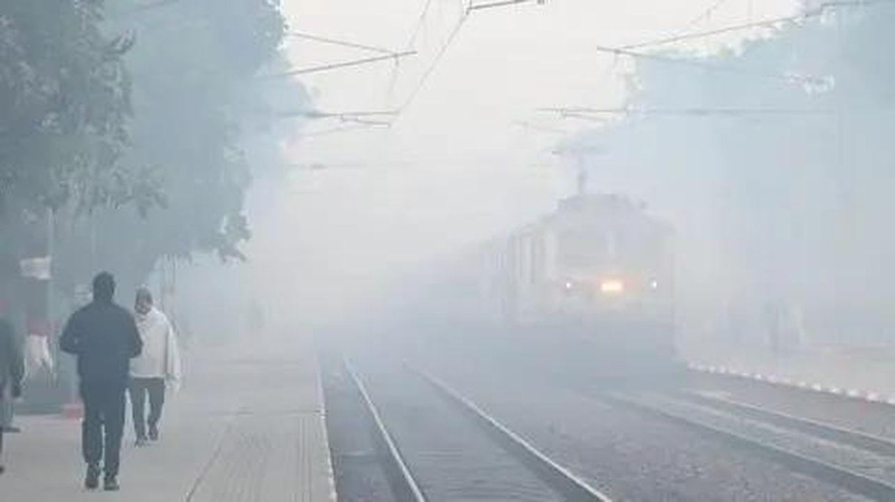 source:BBC World News - Condizioni meteorologiche avverse - Commuters che camminano sui binari mentre un treno arriva in mezzo alla nebbia a New Delhi.