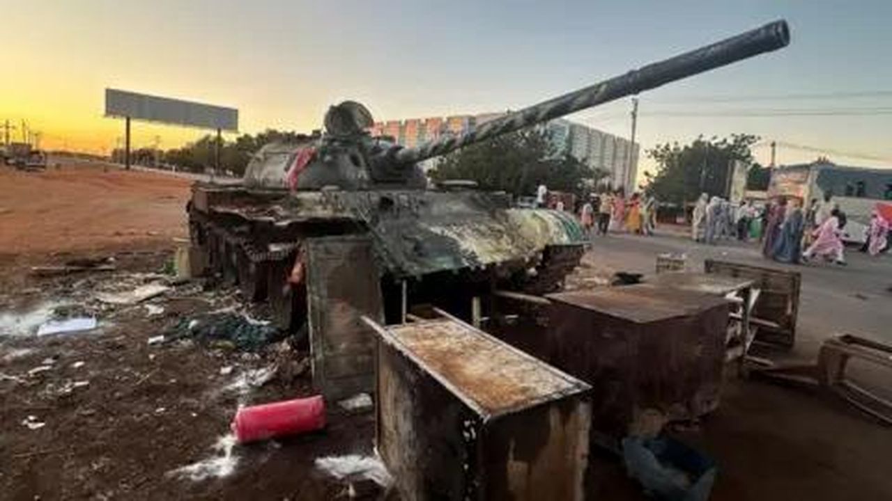 source:BBC World News - Indagini sulle atrocità in Sudan - Un carro armato militare in piedi accanto a una strada a Wad Mdani, con persone in abiti civili nelle vicinanze