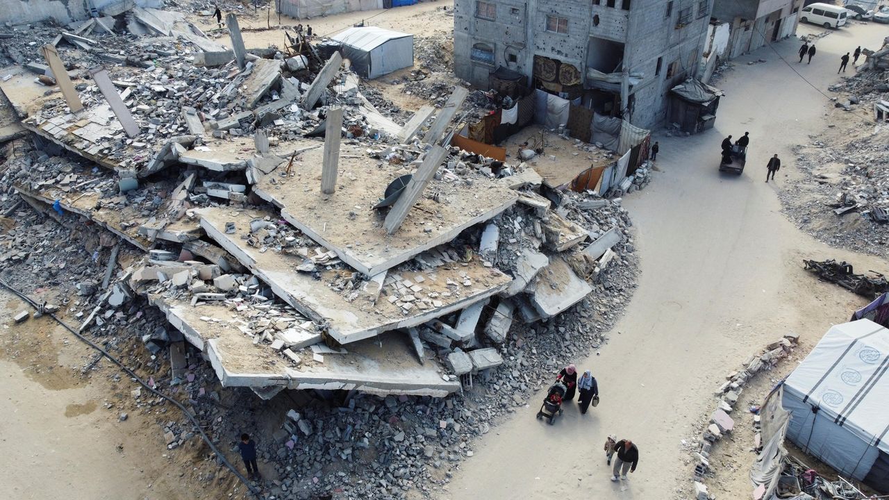 source:AlJazeera - La devastazione della Striscia di Gaza - Palestinesi che camminano tra le macerie di case e edifici.