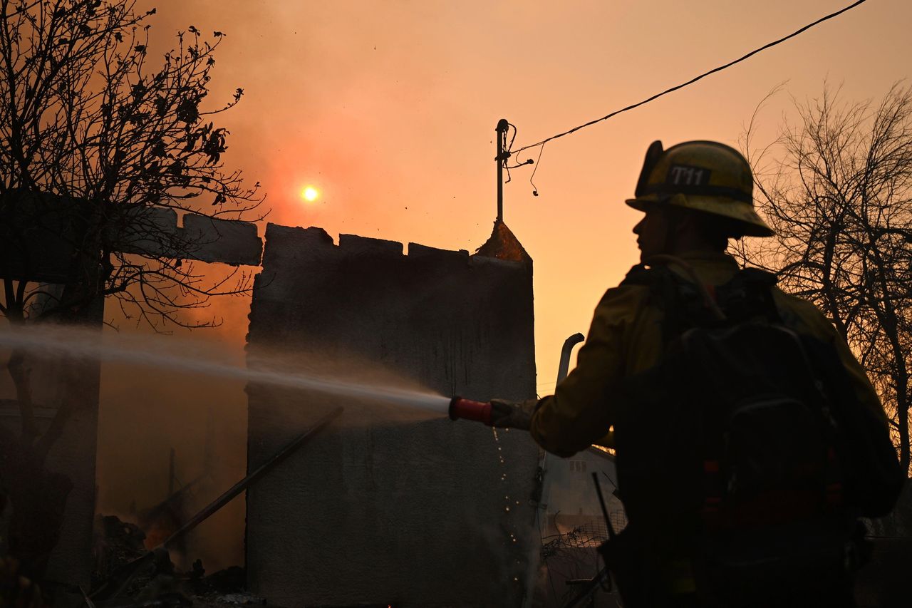 source:Independent - Situazione attuale degli incendi a Los Angeles - Un pompiere irriga una casa dopo l'incendio di Eaton ad Altadena, California.